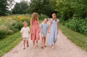 Miller family of four walking hand in hand on a forest path at Lowry Nature Center, Victoria MN